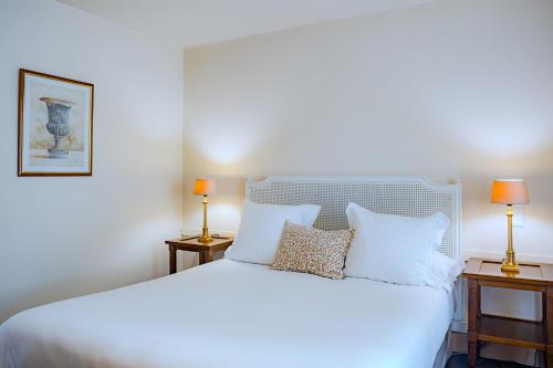 a bedroom with a large white bed with two lamps at Le Cavendish in Cannes