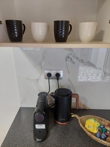 a coffeemaker and cups sitting on a shelf at il vicolo studio in Ágios Matthaíos