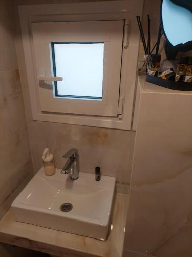a bathroom with a sink and a window at il vicolo studio in Ágios Matthaíos