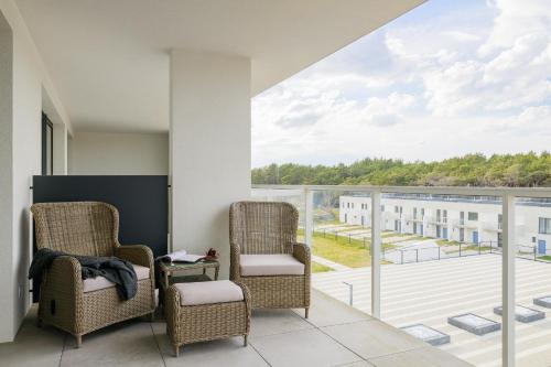a balcony with two chairs and a large window at Apartamenty Marina Rogowo- nowoczesne apartamenty z tarasem- 200m do plaży- między morzem, a jeziorem Resko, parking w cenie! in Rogowo