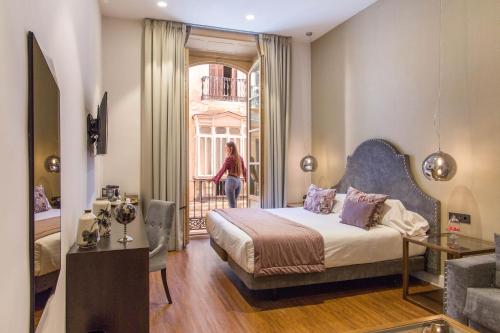 a bedroom with a bed and a woman walking out of a window at Hotel Palacete de Alamos in Málaga