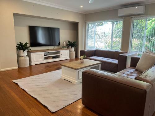 a living room with couches and a flat screen tv at Beryls House in Coffs Harbour
