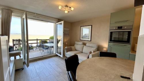 un salon avec un canapé et une table dans l'établissement Les Pieds dans le Sable – Appartement Unique avec Accès Direct à la Plage du Crotoy, au Crotoy
