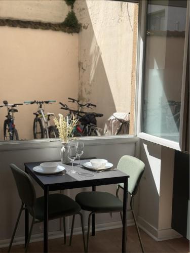 une table et des chaises dans une pièce avec une fenêtre dans l'établissement Le Jungle, à Villeurbanne