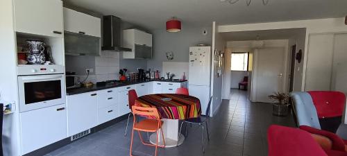 a kitchen with white cabinets and a table with red chairs at Appartement katixa in Bayonne