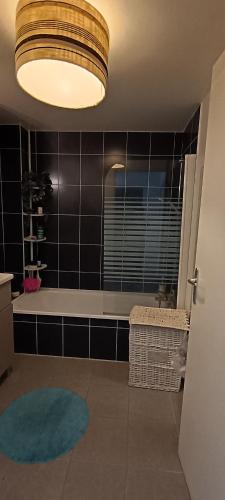 une salle de bain avec une baignoire et un grand luminaire dans l'établissement Appartement katixa, à Bayonne