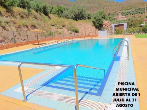 una gran piscina con agua azul y escaleras en Casa Rural El Albergue, en Beires