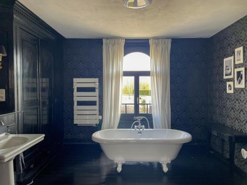 La salle de bains bleue est pourvue d'une baignoire et d'un lavabo. dans l'établissement Appartement 6 personnes, 3 chambres à Mont Saint Eloi, à Mont-Saint-Éloi