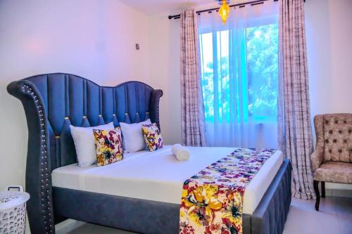 a bedroom with a bed with a blue headboard and a window at Coastal 3BR Vibe, GEM in Nyali in Mombasa