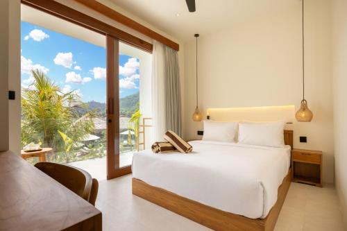 a bedroom with a bed and a large window at Uryah Hotel Lombok in Selong Belanak