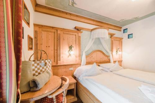 a bedroom with two beds and a table and a window at Hotel Des Alpes in Soraga