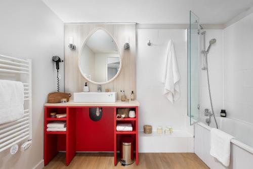 a bathroom with a red vanity and a mirror at Résidence Pierre & Vacances Premium Haguna in Biarritz