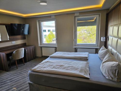 a hotel room with two beds and a television at Hotel City Faber in Worms