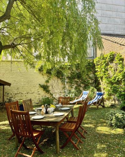 une table et des chaises en bois dans une cour dans l'établissement Maison de famille L'Amandoise, à Le Touquet-Paris-Plage
