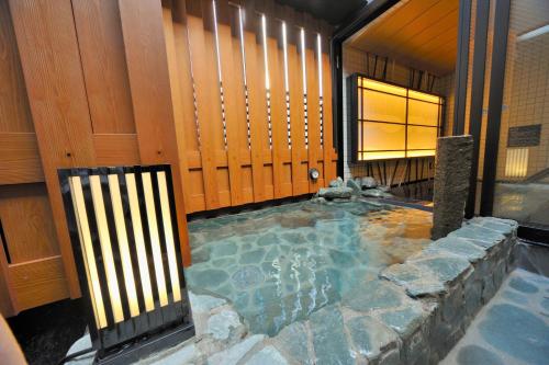 a hot tub in a bathroom with wooden walls at Dormy Inn Ueno Okachimachi in Tokyo