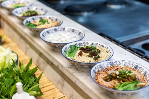 a row of bowls of food on a counter at Lyhn International Hotel Chengdu Taikoo Li in Chengdu