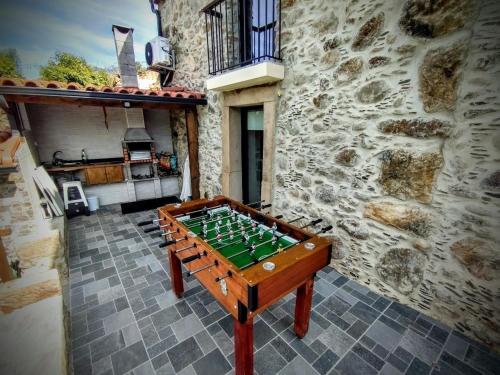 a foosball table in front of a stone building at Quinta dos Picarotos in Vila Nova de Ceira