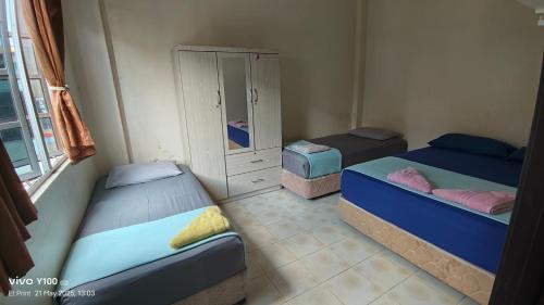 a room with three beds and a cabinet in it at Villa D'Doa Maju in Kuala Terengganu