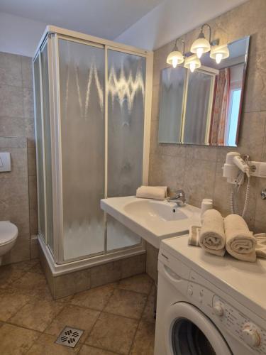a bathroom with a sink and a washing machine at Appartementhaus Am Waalweg in Rifiano