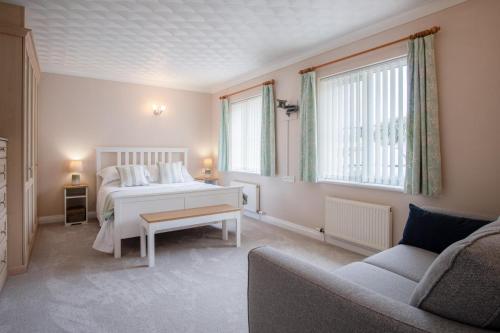 a bedroom with a white bed and a couch at Audreys - 3 Bed Holiday Home - Manorbier in Manorbier