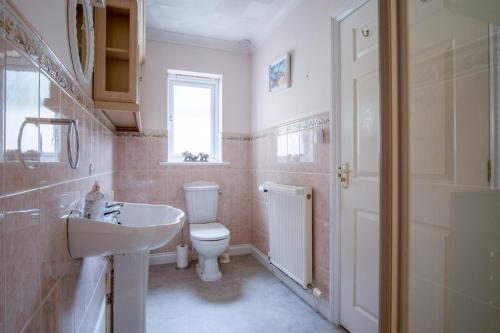 a bathroom with a white toilet and a sink at Audreys - 3 Bed Holiday Home - Manorbier in Manorbier