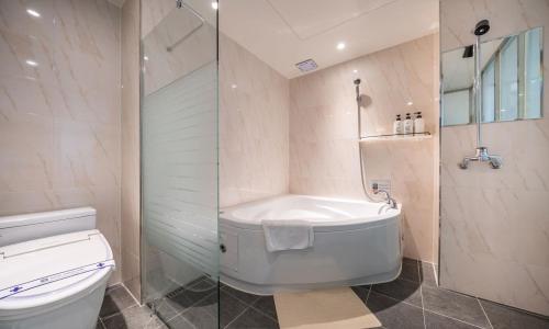 a bathroom with a tub and a toilet and a shower at Gimpo Pentastar Hotel in Gimpo