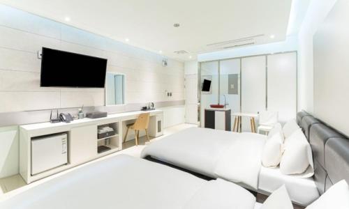 a hotel room with two beds and a flat screen tv at Gimpo Pentastar Hotel in Gimpo