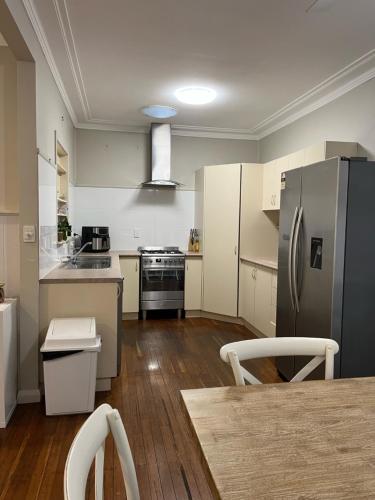 a kitchen with a stainless steel refrigerator and a table at Beryls House in Coffs Harbour