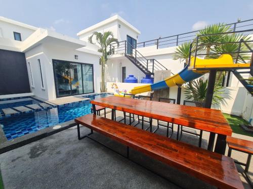 a park bench with a slide in front of a house at Modern Life Pool Villa in Hua Hin