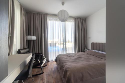 a bedroom with a bed and a desk and a window at Villa Deja Blu with Private Pool in Kalogrea