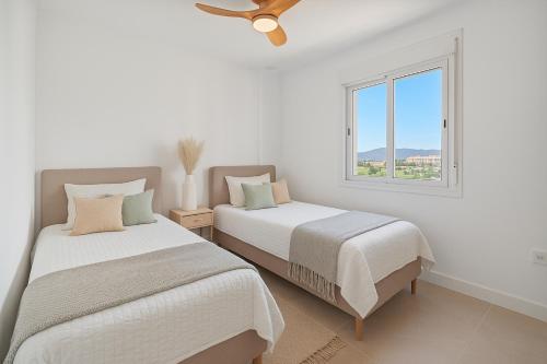 two beds in a white room with a window at Secret View Riviera Del Sol in Sitio de Calahonda