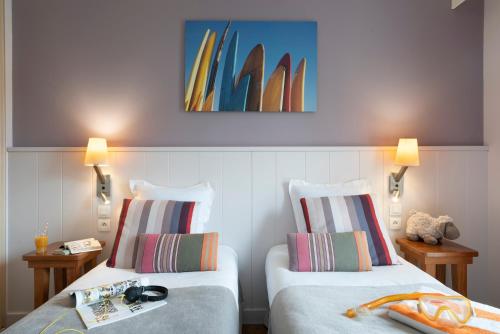 two beds in a room with surfboards on the wall at Résidence Pierre & Vacances Premium Haguna in Biarritz