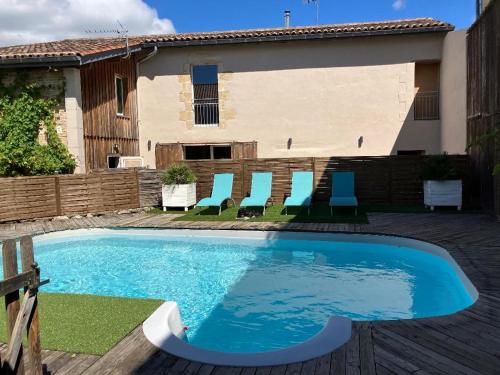 une piscine avec des chaises bleues et une maison dans l'établissement Maison d'Hôtes Martineau, à Saint-Symphorien