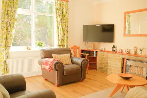 a living room with a chair and a television at 3 Bedroom House by Brookland Stays Serviced Accommodation Short Lets Leeds in Yeadon