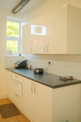 a kitchen with white cabinets and a black counter top at 3 Bedroom House by Brookland Stays Serviced Accommodation Short Lets Leeds in Yeadon
