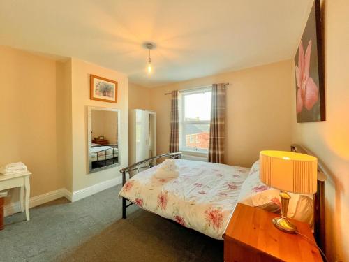 a bedroom with a bed with a lamp and a window at 3 Bedroom House by Brookland Stays Serviced Accommodation Short Lets Leeds in Yeadon