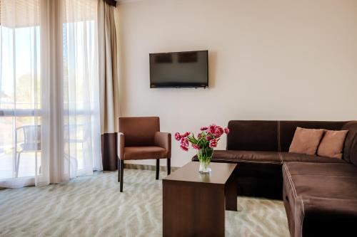 a living room with a couch and a tv at Hotel Emocja SPA in Mielno
