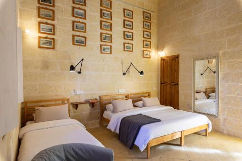 a bedroom with two beds and a mirror at Gozobreak Farmhouses in Kerċem