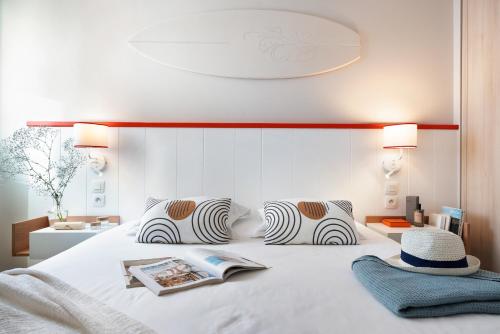 a bedroom with a white bed with a hat on it at Résidence Pierre & Vacances Premium Haguna in Biarritz