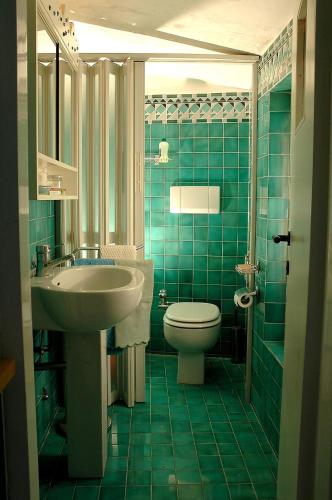 a green tiled bathroom with a sink and a toilet at Appartamento con Terrazza superpanoramica in Madonna del Sasso
