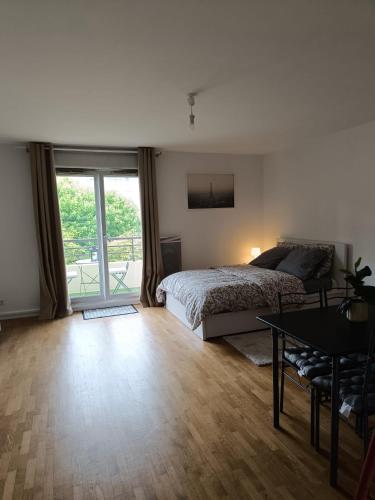une chambre avec un lit, une table et une fenêtre dans l'établissement Appartement Cosy, 30 minutes de Paris, à Carrières-sous-Poissy