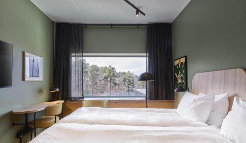 a bedroom with a large bed and a large window at Scandic Alvik in Stockholm