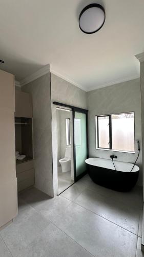 a bathroom with a bath tub and a toilet at CELONIA VILLA - Euphoria Golf Estate in Naboomspruit