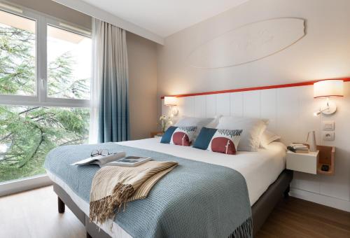 a bedroom with a large bed and a window at Résidence Pierre & Vacances Premium Haguna in Biarritz