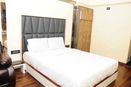 a bedroom with a large white bed with a black headboard at Vgrand in Ooty