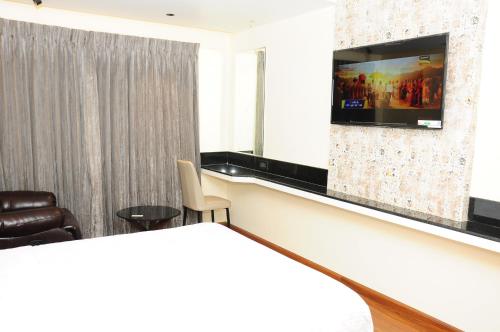 a room with a bed and a tv on a wall at Vgrand in Ooty