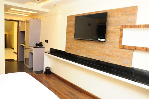 a hotel room with a flat screen tv on a wall at Vgrand in Ooty