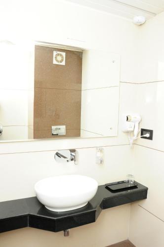 a bathroom with a white sink and a mirror at Vgrand in Ooty