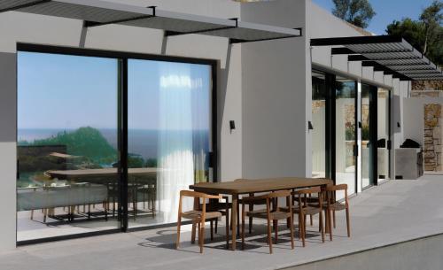 a house with a table and chairs on a balcony at Scirocco Luxury Villas & Suites in Vasiliki