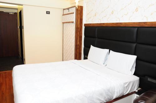a bedroom with a white bed with a black headboard at Vgrand in Ooty